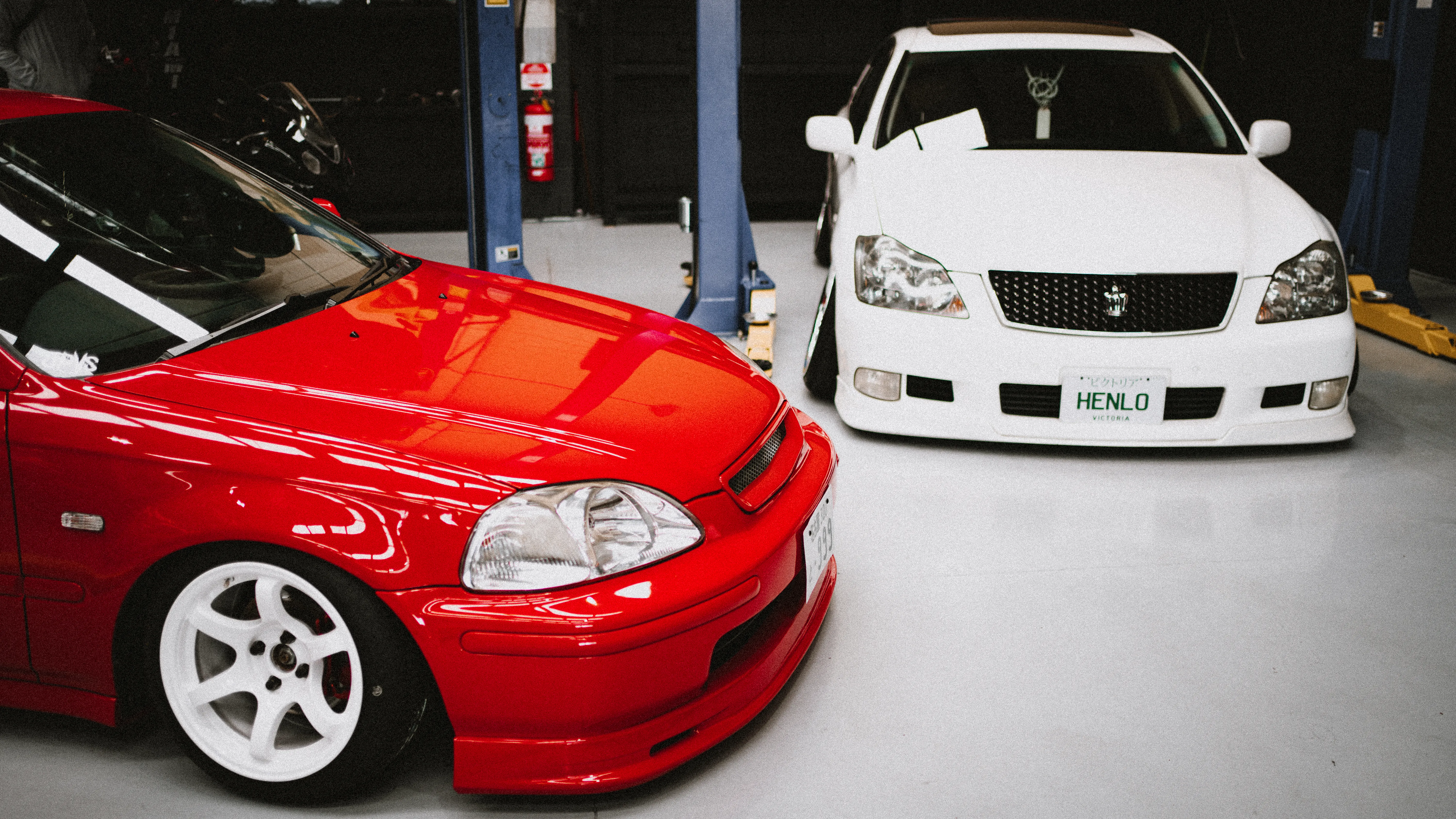 Red Honda Civic and white Toyota Crown side by side in the workshop