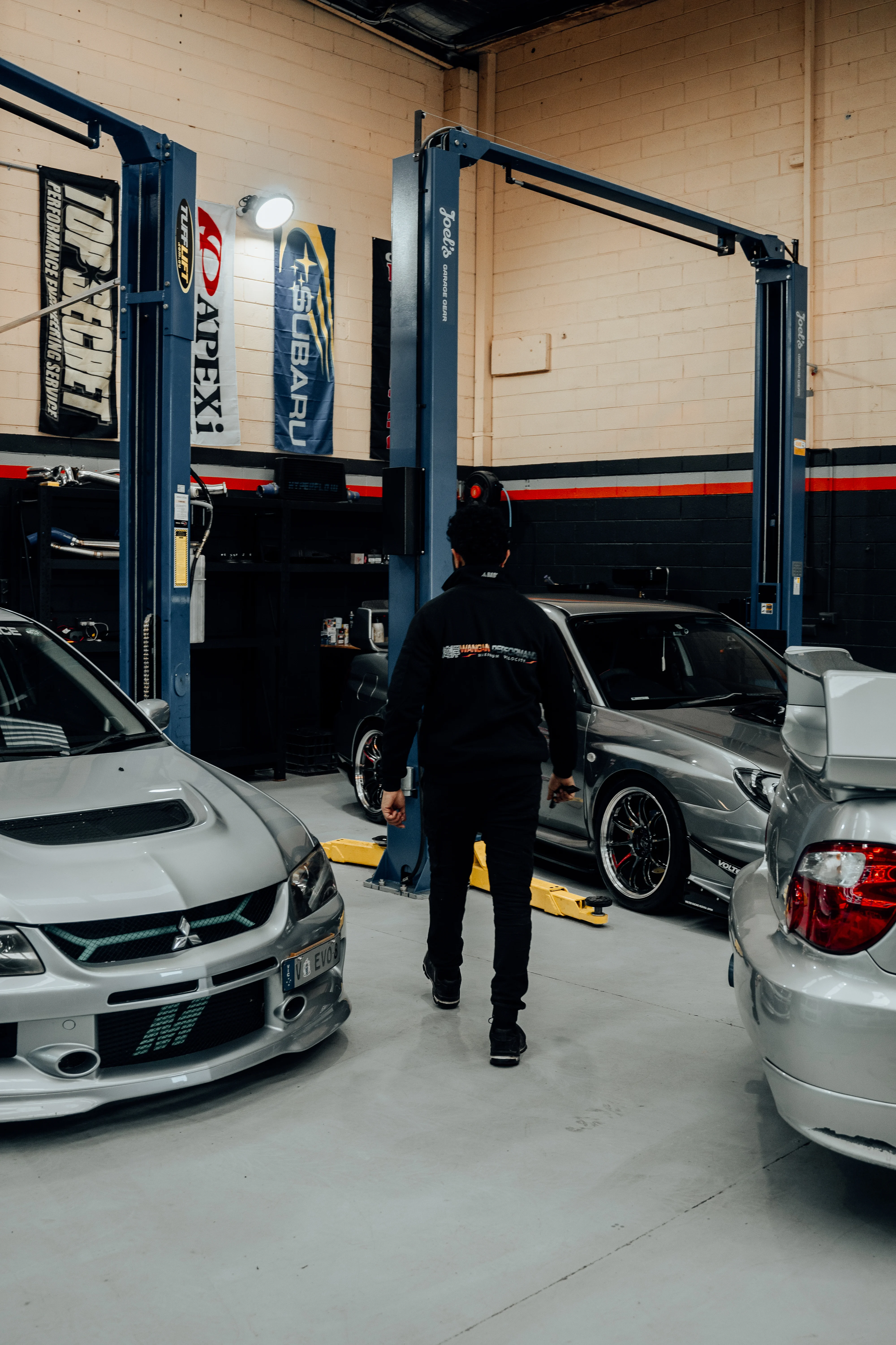 Wangan Performance team member walking between cars in the workshop